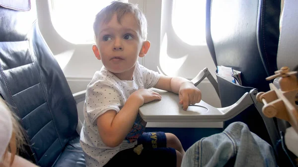 Маленький мальчик, напуганный во время полета в самолете, смотрит на мать — стоковое фото