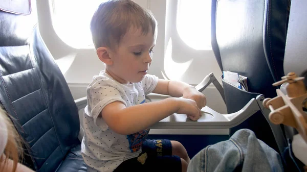 Retrato del niño pequeño sentado en el avión y jugando con juguetes — Foto de Stock