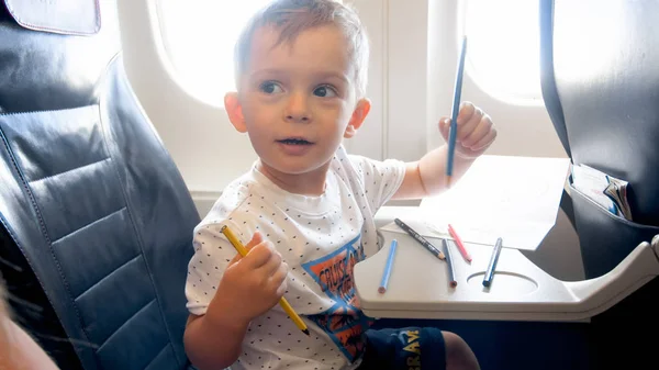 Retrato de niño sonriente feliz volando en avión y sosteniendo lápices de colores — Foto de Stock