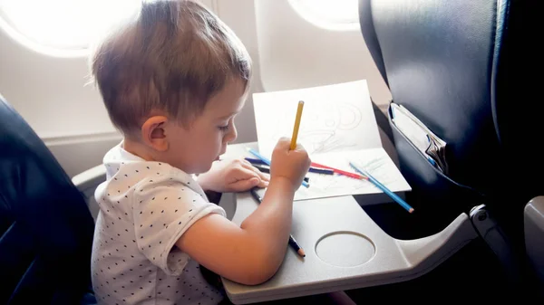 Тонированный портрет маленького мальчика, рисующего в самолете во время полета — стоковое фото