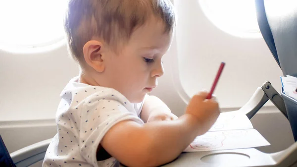 Imagen de primer plano del niño pequeño dibujando en vuelo largo en avión — Foto de Stock