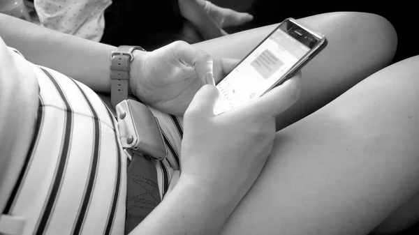 Schwarz-Weiß-Bild weiblicher Flugpassagiere, die während des Fluges SMS auf ihr Smartphone tippen — Stockfoto
