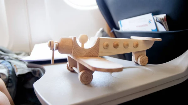 Imagen de primer plano del avión de madera en miniatura en la mesa del asiento delantero en el avión a reacción — Foto de Stock