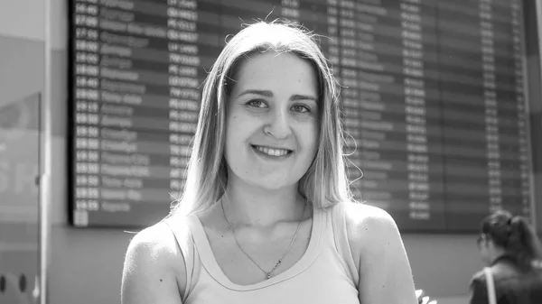 Preto e branco retrato de bela mulher sorridente posando no terminal do aeroporto antes do voo — Fotografia de Stock