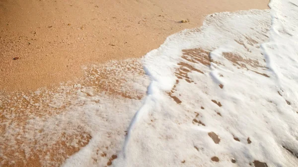 Крупный план морских волн, катящихся по пляжу с красивым золотым песком на закате . — стоковое фото