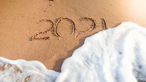 Close-up beeld van 2021 getallen wordt gewassen uit natte zand op strand door de zee-Golf. Concept van Nieuwjaar, Kerstmis en reizen op wintervakantie. — Stockfoto