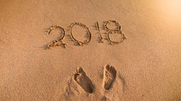 Närbild bild av 2018 nummer och fotavtryck på våt sand på ön beach. Begreppet nyår, jul och resa på vintersemester. — Stockfoto