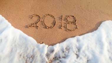 Okyanus dalgalarının 2018'de ıslak kuma yazılmış sayıların yakın çekim fotoğrafı. Kış tatillerinde kutlama ve seyahat kavramı.