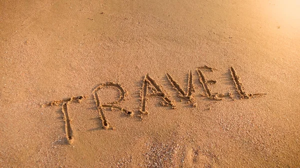 Afbeelding van woord reizen inscriptie op nat zand op het strand van de Oceaan bij zonsondergang. Concept van toerisme, reizen, reizen en reizen. — Stockfoto