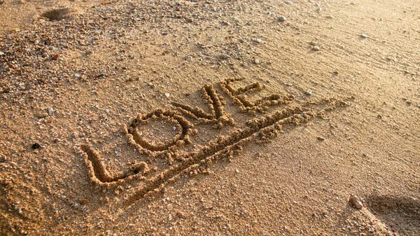 Closeup image of word love written on wet sand at beach — Stock Photo, Image