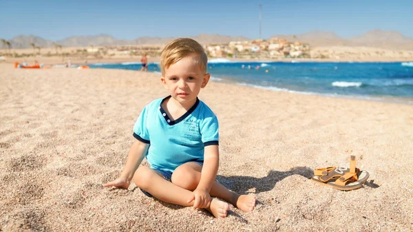 Mały 3-letni chłopiec siedzi na piasku na plaży — Zdjęcie stockowe