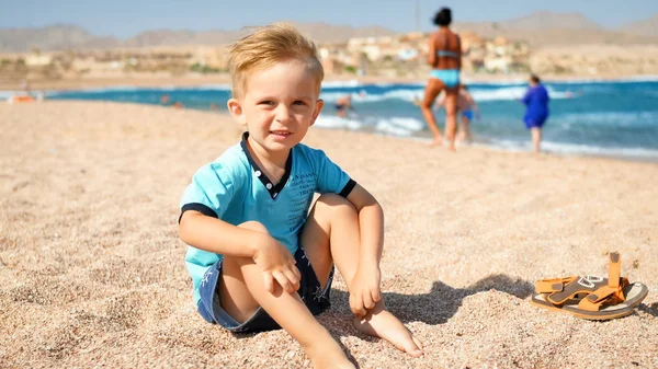 Portret uroczych malucha chłopca ciesząc siedzi na plaży na morzu — Zdjęcie stockowe