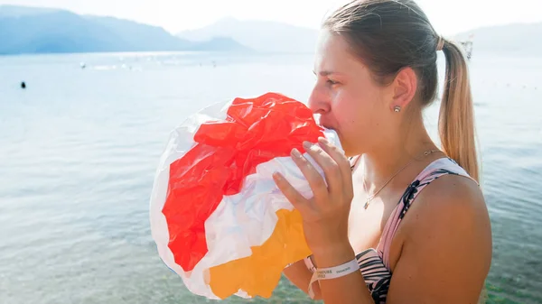 Closeup portrét nádherné mladé ženy nafukující barevný plážový míč — Stock fotografie
