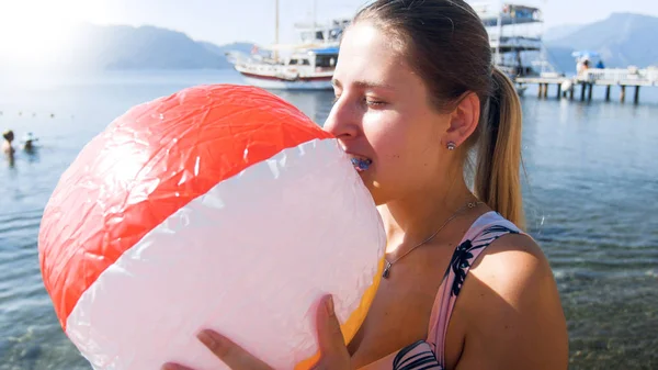 口でカラフルなビーチボールを膨らませる若い女性のクローズアップ写真 — ストック写真