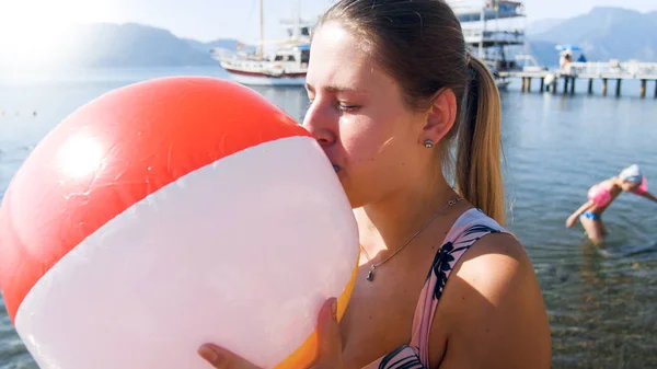 Retrato de mujer joven en traje de baño soplando bolas de colores en la playa de mar —  Fotos de Stock