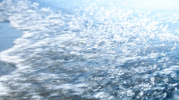 Imagen de cerca de las olas azules del mar rodando sobre la playa de arena. Resumen fuera de foco de la imagen — Foto de Stock