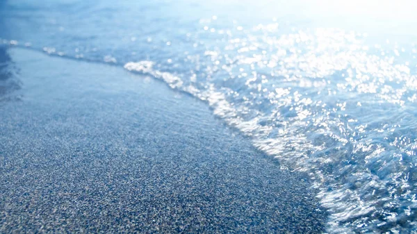 Imagen de cerca de las olas azules del mar rodando sobre la playa de arena. Resumen fuera de foco de la imagen — Foto de Stock