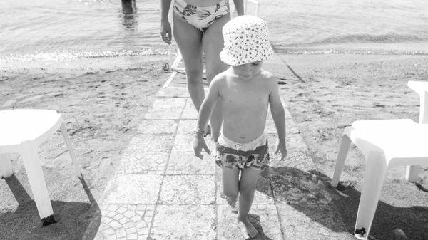 Черно-белый образ маленького ребенка, гуляющего по пляжу после купания в море — стоковое фото
