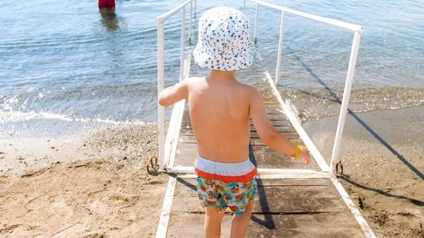 Foto vista traseira do menino caminhando no mar — Fotografia de Stock
