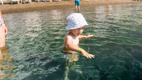 Cute Little Boy stoi w morzu i dotykając wody z rąk — Zdjęcie stockowe