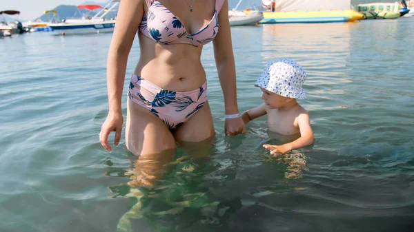 Młoda matka trzyma dziecko za rękę i spaceruje w ciepłym morzu — Zdjęcie stockowe