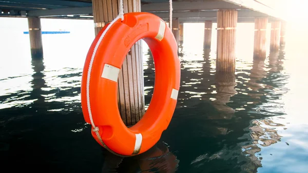 Närbild foto av röd Spara ring hängande träbrygga. Säkerhet på havsvatten — Stockfoto