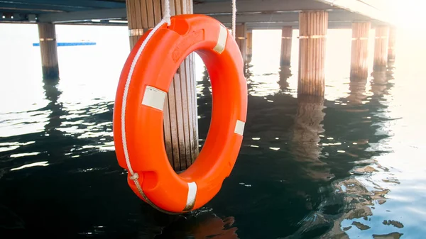 Closeup toned image of orange life saving buoy hanging at wooden pier — Stock Photo, Image