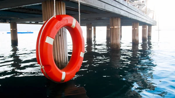 Närbild foto av röd Spara ring hängande träbrygga. Säkerhet på havsvatten — Stockfoto