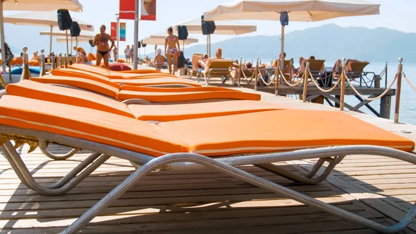Closeup image of straight rows of sun beds on wooden pier at bright sunny day — Stock Photo, Image