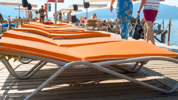Closeup photo of sunbeds with towels and matrasses on wooden pier at sea shore. Concept of summer holidays on beach — Stock Photo, Image