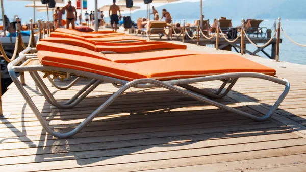 Розмиті зображення людей, які відпочивають на шезлонгах на дерев'яному пірсі в морі. Літні канікули на пляжі — стокове фото