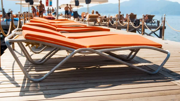 Närbild foto av solstolar med handdukar och matrasses på träbrygga vid havet. Begreppet sommarlov på stranden — Stockfoto