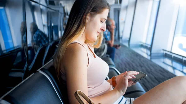 Closeup portrait of smiling beautiful woman browsing internet via wi-fi on smartphone at airport terminal — Stock Photo, Image