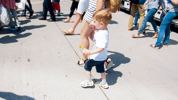 Little 2 years old toddler boy holding mother by hand and walking on the bus stop — Stock Photo, Image