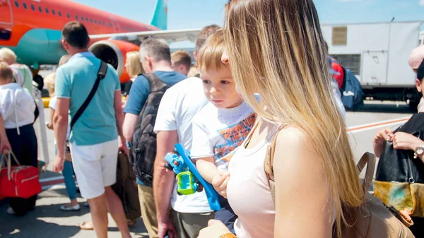 Retrato da jovem segurando seu menino e esperando para embarcar no avião — Fotografia de Stock