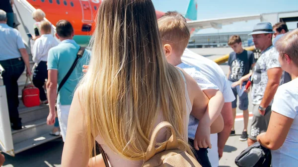 Visão traseira imagem da bela mulher oung com filho da criança subindo a escada para o avião — Fotografia de Stock