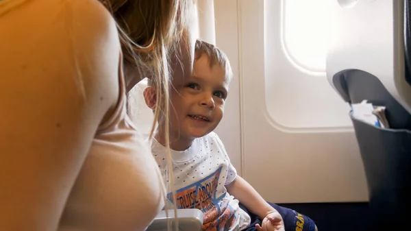 Toned retrato de jovem mãe beijando seu filho criança no avião durante o primeiro voo — Fotografia de Stock