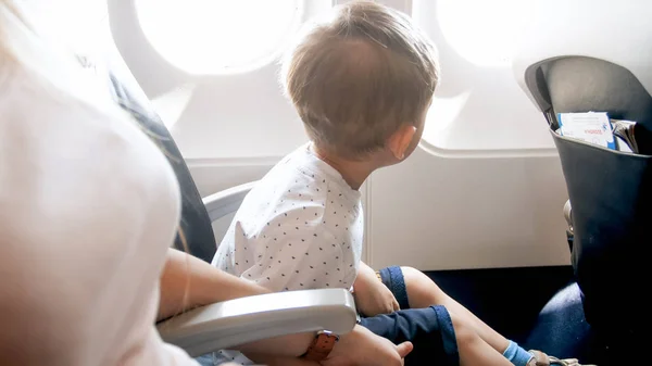 Kleiner Kleinkind-Junge sitzt auf Flugzeugpassagiersitz und schaut durch Scheinwerfer — Stockfoto