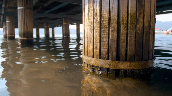 Immagine ravvicinata di vecchie colonne di legno in crollo che reggono il molo sulla spiaggia — Foto Stock