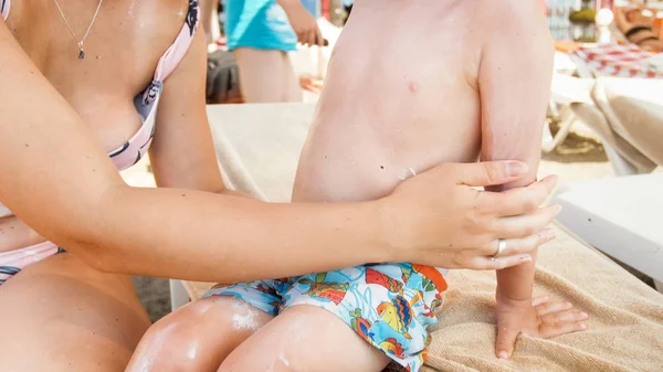 Bella giovane donna applicazione e sfregamento crema solare lozione nella sua pelle bambini prima di prendere il sole sulla spiaggia — Foto Stock