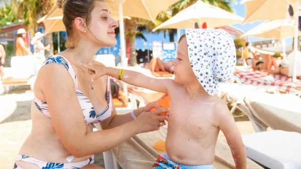 Nahaufnahme Porträt einer glücklich lächelnden Familie mit kleinem Kind, die Sonnencreme am Strand aufträgt — Stockfoto