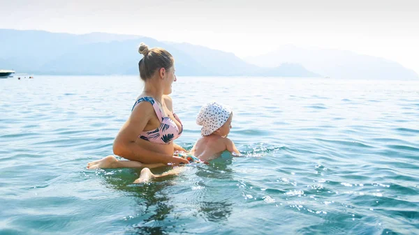 Hermosa mujer joven enseñando a su pequeño niño a nadar en elake th —  Fotos de Stock