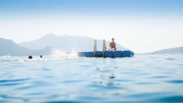 Размытое фото плавучей платформы в спокойных морских волнах на летнем курорте — стоковое фото