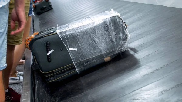 Крупним планом фото сумки і валізи на рухомому конвеєрному поясі в зоні багажу в терміналі аеропорту — стокове фото