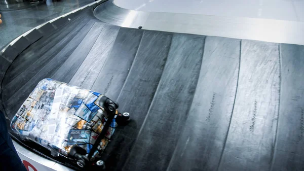 Imagem de close-up da mala deitada na linha de reclamação de bagagem no moderno terminal do aeroporto — Fotografia de Stock