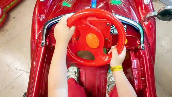 Immagine da primo piano del piccolo bambino che tiene la ruota sterlina nell'auto giocattolo elettrica — Foto Stock