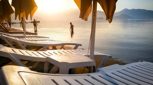 People swimming in calm sea at sunset against shining sun — Stock Photo, Image