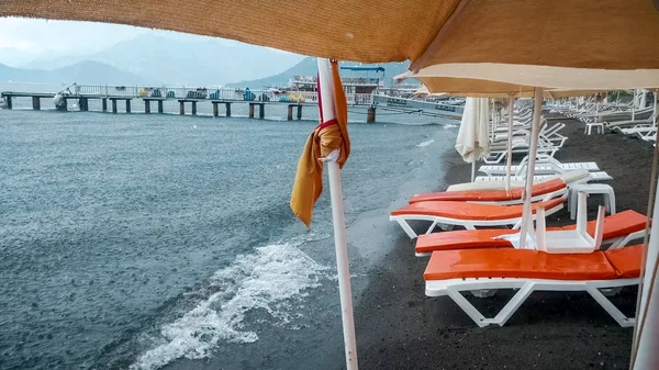 Esvaziar espreguiçadeiras na praia do mar durante a chuva forte — Fotografia de Stock