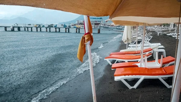 Сильный дождь на пустом морском пляже. зонтики и шезлонги — стоковое фото