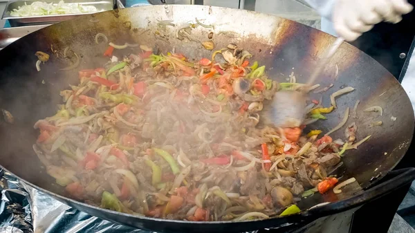 Immagine di primo piano di cuoco mescolando verdure che friggono in padella wok a cucina all'aperto — Foto Stock